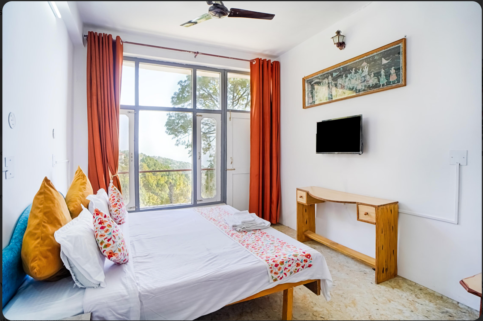 Deluxe room with double bed, orange curtains and private balcony
